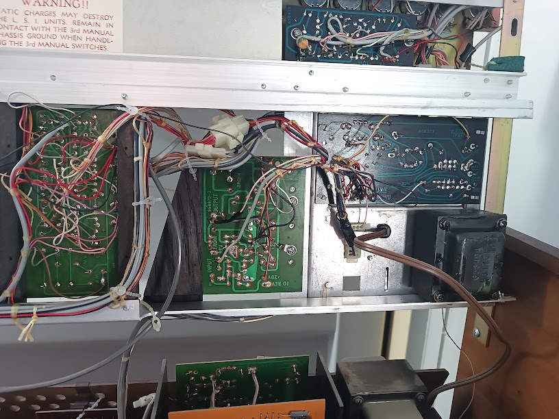 Circuit boards behind the upper keyboard — multiple green PCBs with dense point-to-point wiring, a transformer, and Wurlitzer connectors