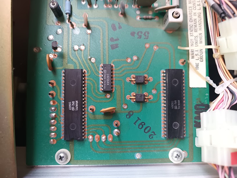 Close-up of the LSI board showing two 40-pin divider-keyer ICs, the TOS chip, and two smaller ICs on a green PCB with test points