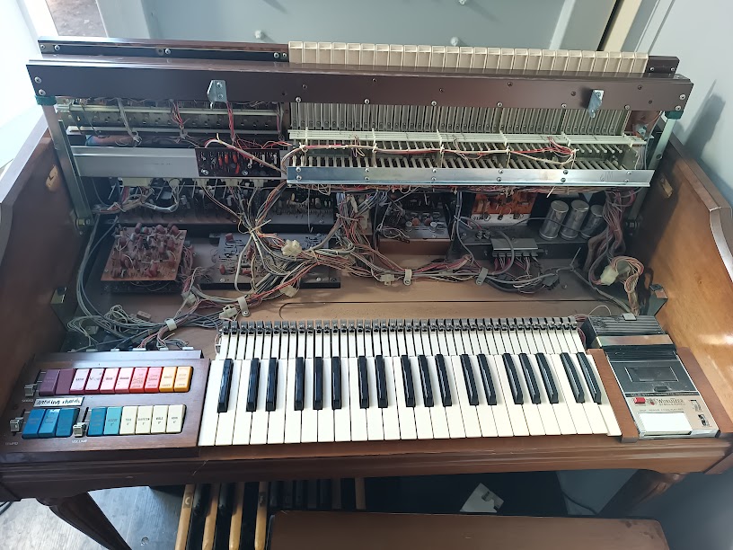 Console with lower manual area exposed — upper circuit boards, wiring harnesses, electrolytic capacitors, and Orbit III area all visible