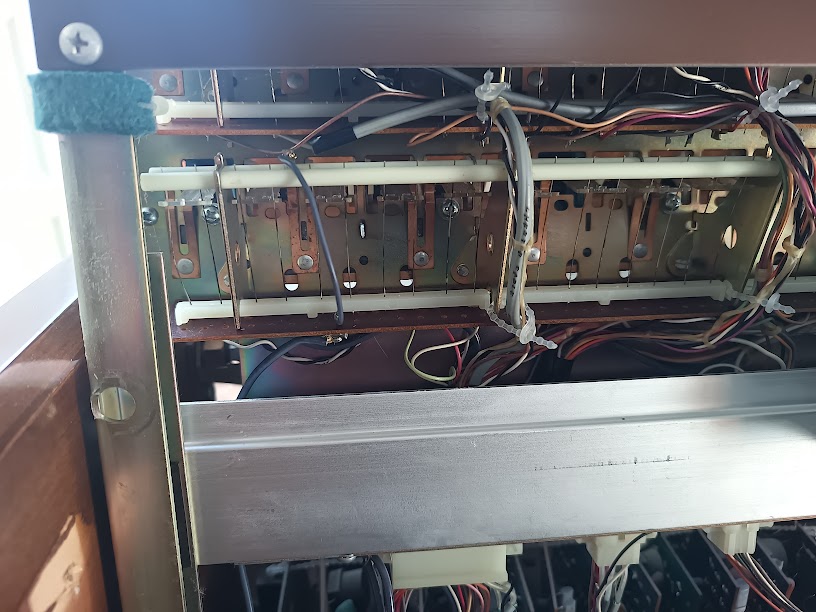 Underside of the stop tab switch assembly showing copper contact bars and mounting hardware