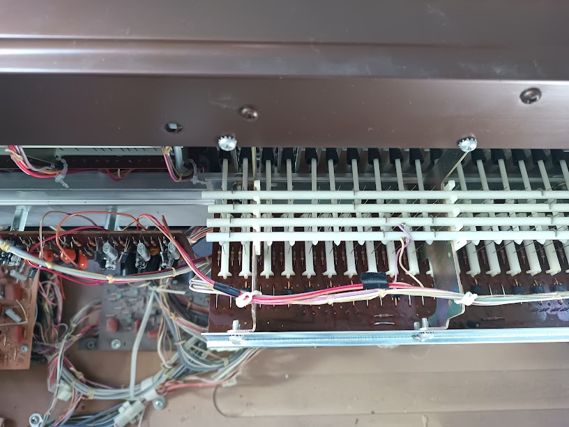 Close-up of key contact wire whiskers viewed from above — rows of fine wires extending from the rear of the keys toward bus bars