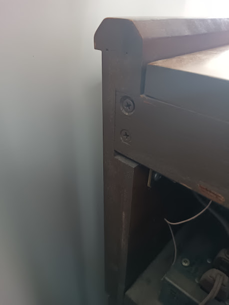 Phillips screw at the top lid corner where it meets the cheek block