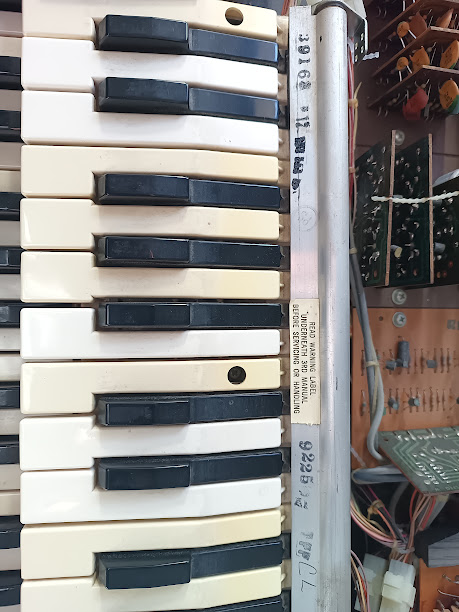 Upper manual tilted up showing the side profile — a warning label and metal hinge rod are visible